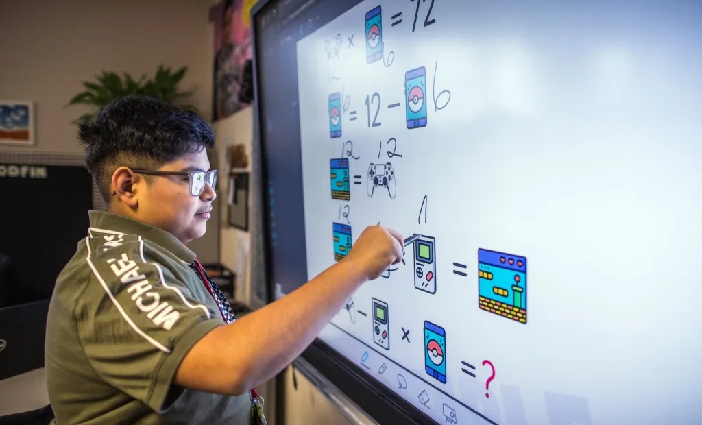 How one district has diversified math classes without the controversy: boy works on smartboard in class solving math problems