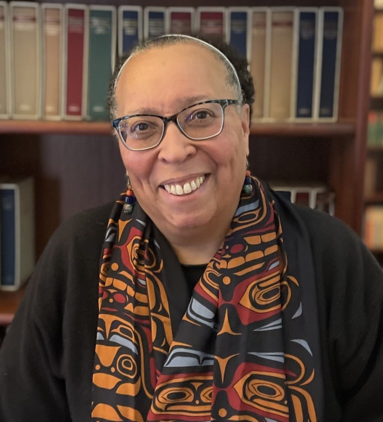Karen Pittman opinion: Black woman with dark-frame glasses an hair pulled back wearing dark jacket and long, colorful scarf with bookshelf in the background.