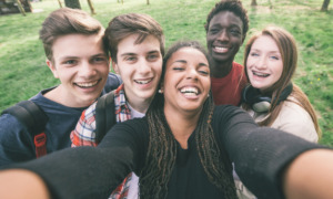 Peacebuilding youth opportunity: Group of five teens standing close together taking selfie