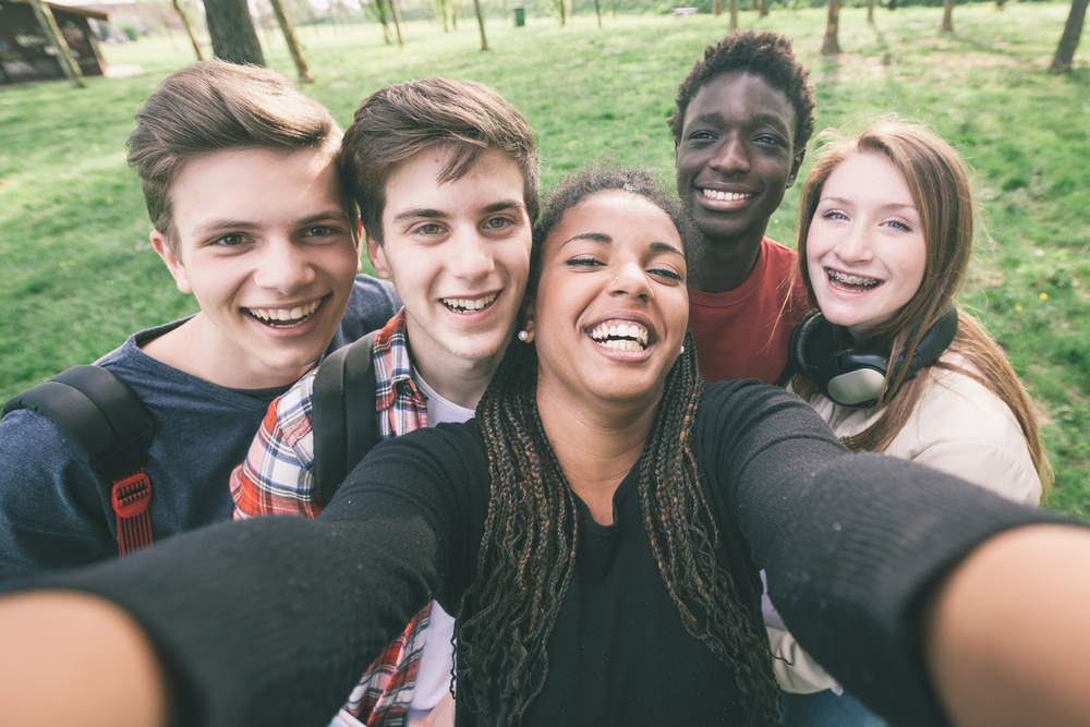 Peacebuilding youth opportunity: Group of five teens standing close together taking selfie