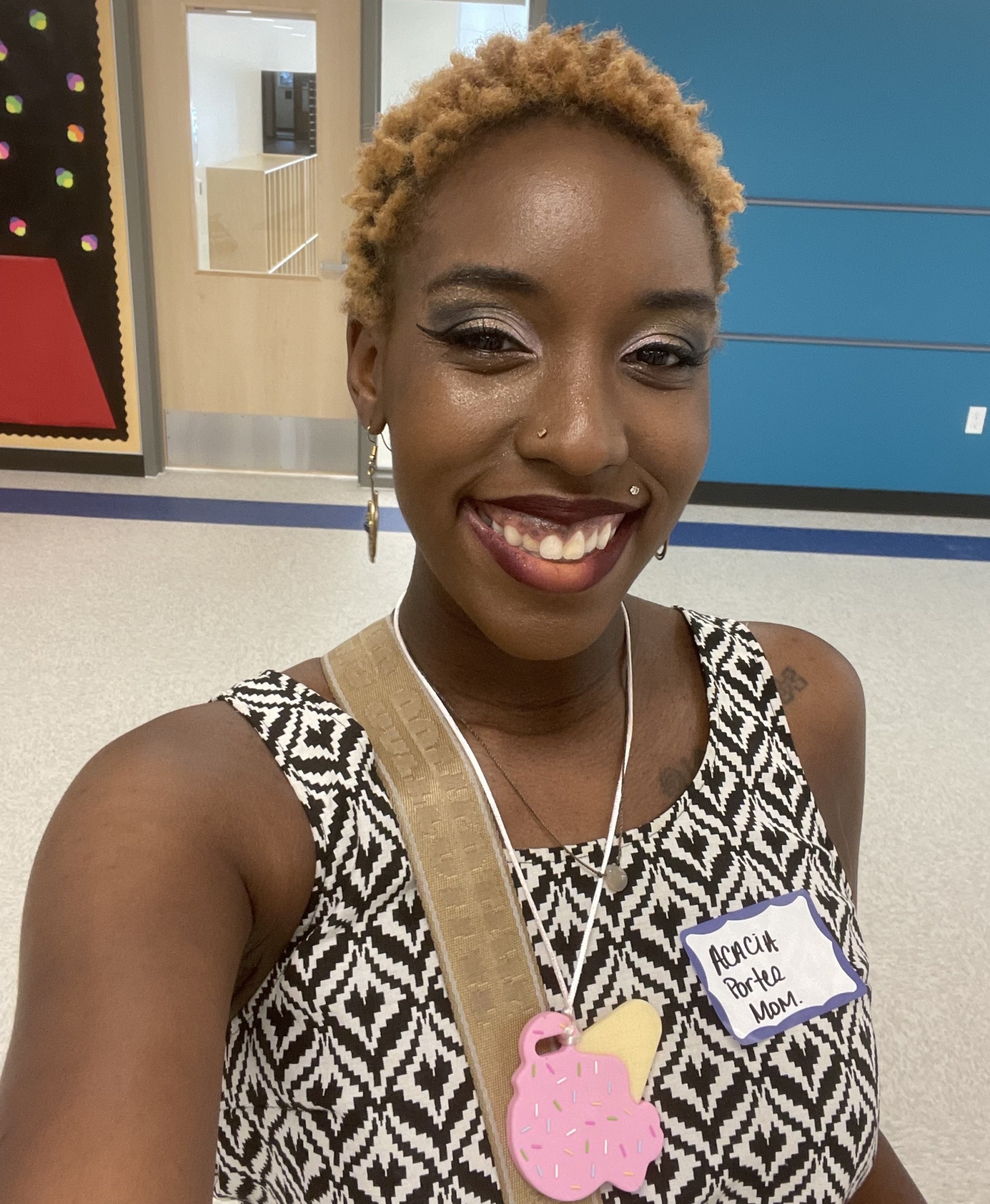 Black charter school: Black woman with short blonde hair in black and white sleeveless geometric print top smiles into camera