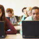 Digital SAT: high school students sit at classroom desks working on laptop computers