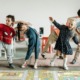 Childcare private equity regulations: Several early primary kids dance and stretch while in a line inside pre-school classroom