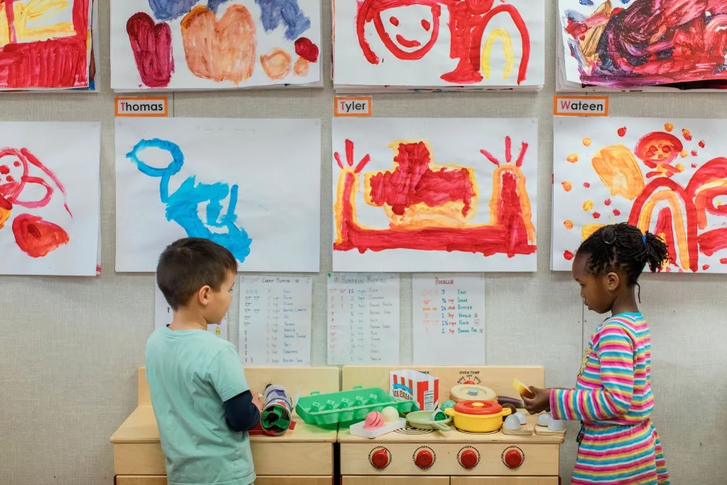 Universal prekindergarten is coming to California_bumpy rollout and all: two children playing with things in front of wall of children's art