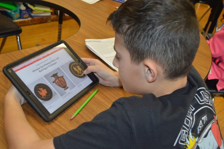 How 2 teachers use AI behind scenes: student looking at images of vases on ipad in classroom