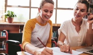 Lessons from tutoring revolution in public education: white woman with brown hair helping white, lighter-haied female student on schoolwork