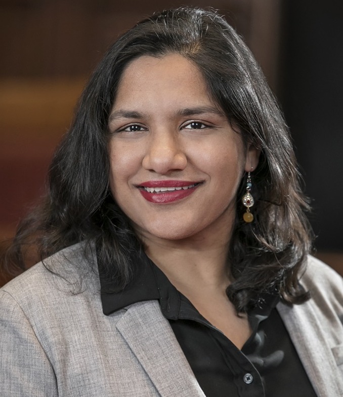 Guaranteed Income: Headshot Black woman with long, black hair in light gray suit with black shirt
