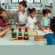 Childcare: Mixed ethnic group of preschoolers sit at activity table with female teacher