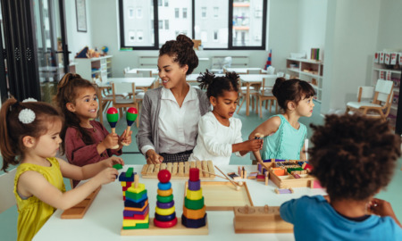 Child care teachers: Mixed ethnic group of preschoolers sit at activity table with female teacher