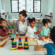 Child care teachers: Mixed ethnic group of preschoolers sit at activity table with female teacher