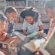 Touch and literacy: Group of middle school students sitting on a library rug in circle reading with sun rays shining down on them