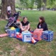 Parents tote toddlers to D.C. for child tax credit and child care: two women, one with a baby, sitting and talking on a blanket in a park with protest materials