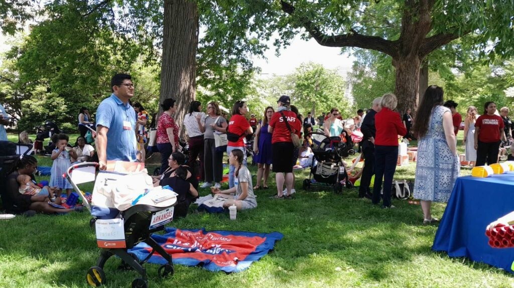 Parents tote toddlers to D.C. for child tax credit and child care: large group of parents, children and others gathered in a park