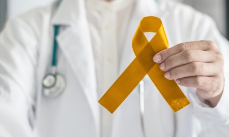 Childhood cancer research support grants: doctor holding golden childhood cancer awareness ribbon