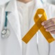 Childhood cancer research support grants: doctor holding golden childhood cancer awareness ribbon