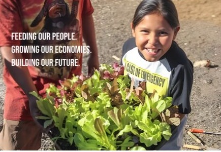Indigenous agriculture education: Young Native boy holds tray full of leafy green plants standing next to Native Elder man