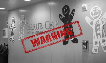 Shrub Oak School investigation: photo of wall with school name surrounded by 3 very large cutouts of gingerbread men colored in child-like style all with a large red "warning" sign with thick border around it