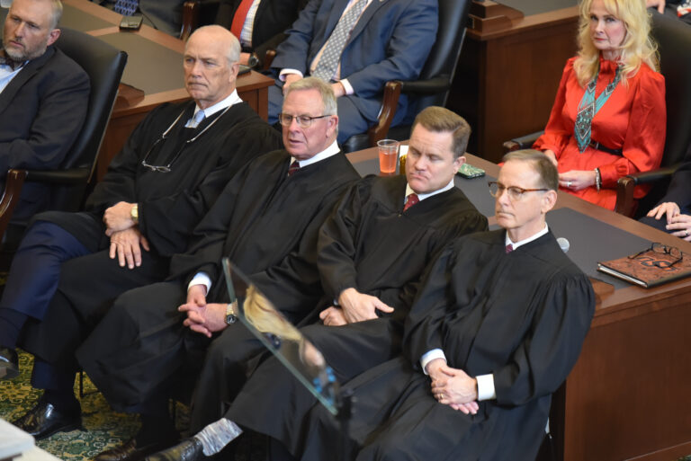 Oklahoma-strikes-down-religious-charter-school: 4 older white men in black judges ribes sit with nads in laps on lap in a row of wood chairs in an audience chanber