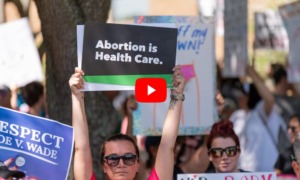 Abortion bans: Close up of crowd of adults at abortion rights rally with signs held up