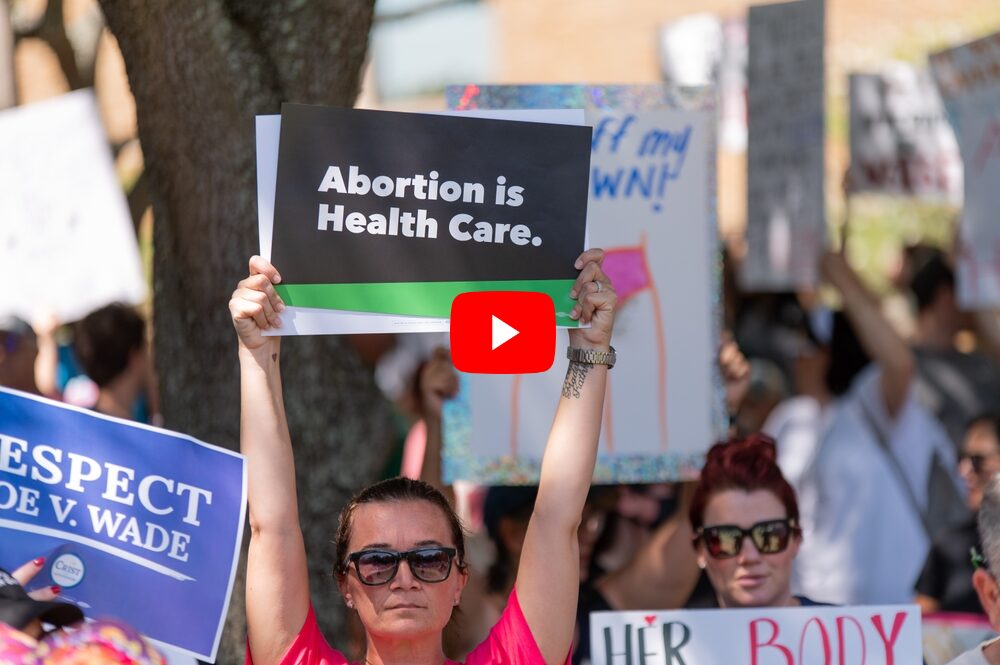 Abortion bans: Close up of crowd of adults at abortion rights rally with signs held up