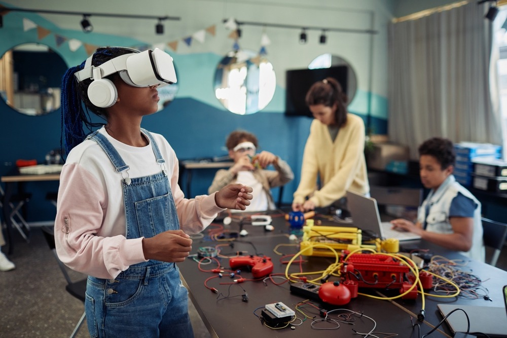 Teens and technology: Students in a school technology classroom using various gear like laptops, VR headsets, and building with electronic kits.