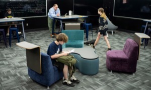 COVID aid funded big repairs at high-poverty schools_Will that give academics a boost too: updated school workspace with students working and walking and teacher in background