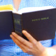 Bible teaching Oklahoma public schools: Close up of a man or woman reading a navy blue Christian Bible.