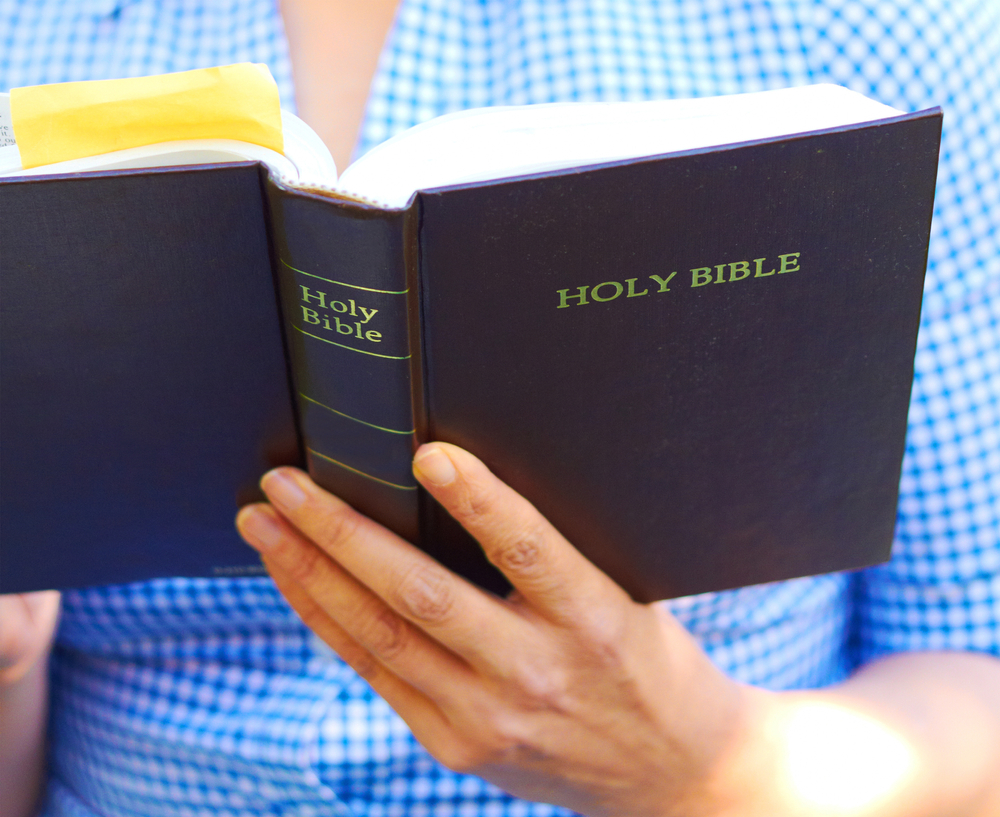 Bible teaching Oklahoma public schools: Close up of a man or woman reading a navy blue Christian Bible.