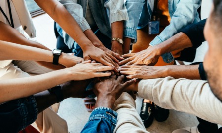 Community development and empowerment grants: group of diverse people putting their hands in a teamwork huddle