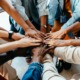 Community development and empowerment grants: group of diverse people putting their hands in a teamwork huddle