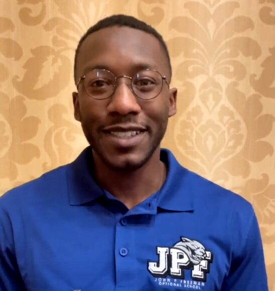 Elementary school farmers market: Mugshot of Jeromy Payne, a black male with short dark hair, a beard, wire-rimmed glasses and a light blue polo shirt with a logo. "JPF" white