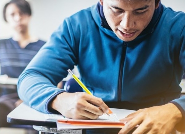 native youth education and job training grants: male student works at desk in school