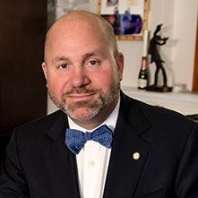 Cayuhoga juvenile defenders: MIDDLE-AGED BALDING MAN WITH SHORT BROWN BEARD IN BLACK SUIT, WHITE SHIRT AND DARK BLUE BOW TIE