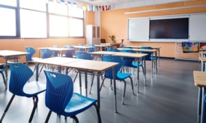 From chronic absence to chosen presence: chronic absenteeism, Classroom with light wood desks and bright blue chairs and no students