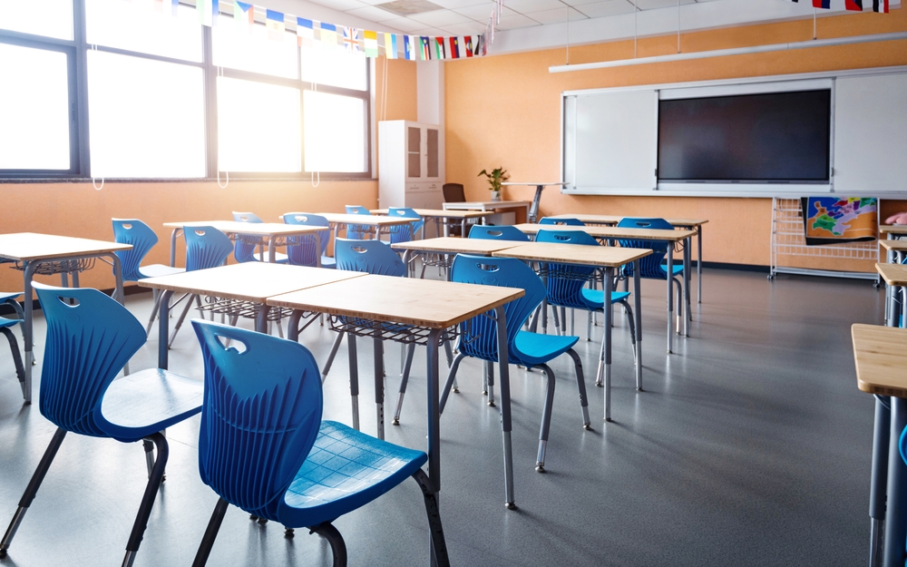 Reduce chronic absenteeism: Classroom with light wood desks and bright blue chairs and no students