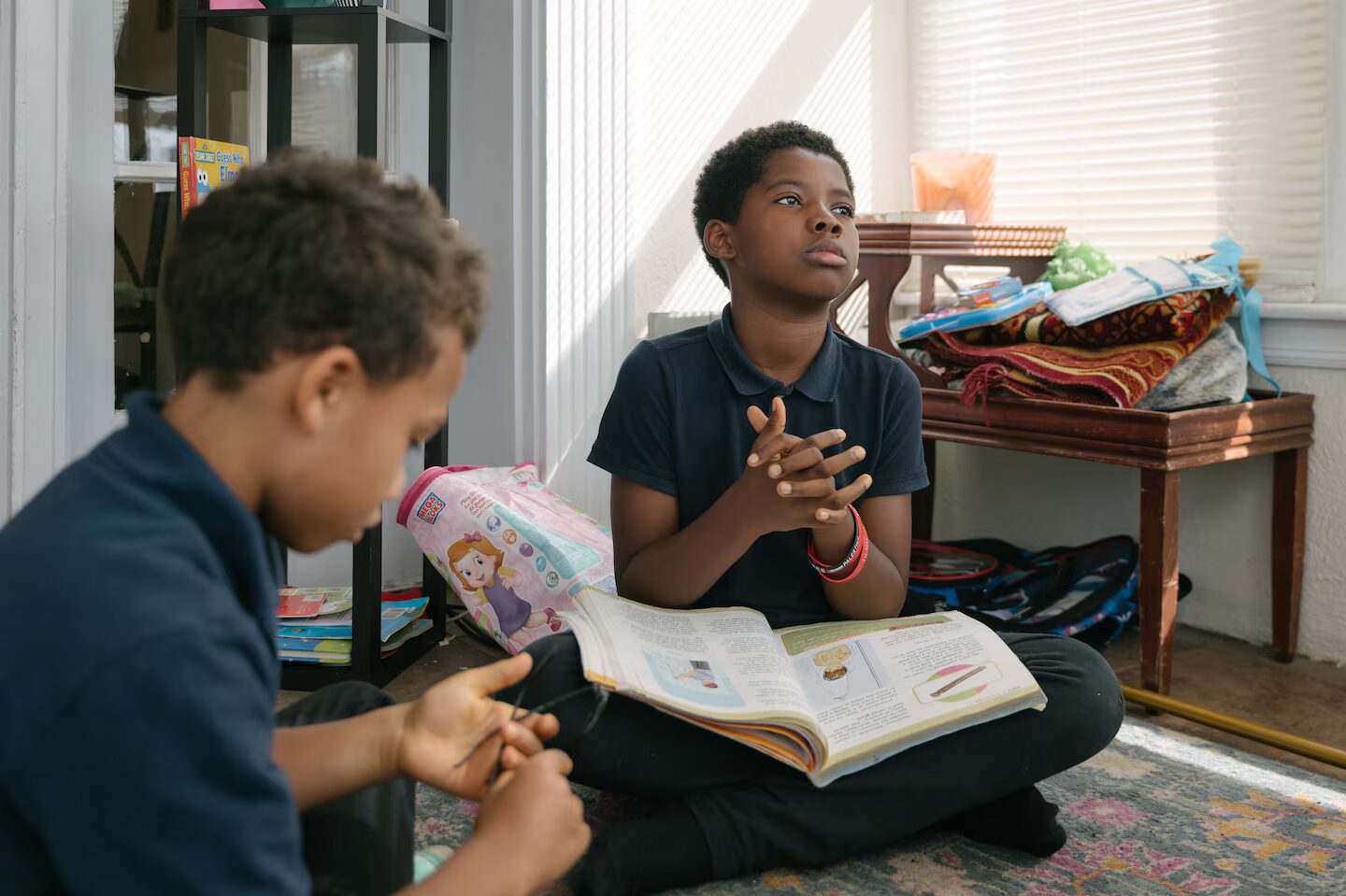 Online school: Two young children sit on floor with books