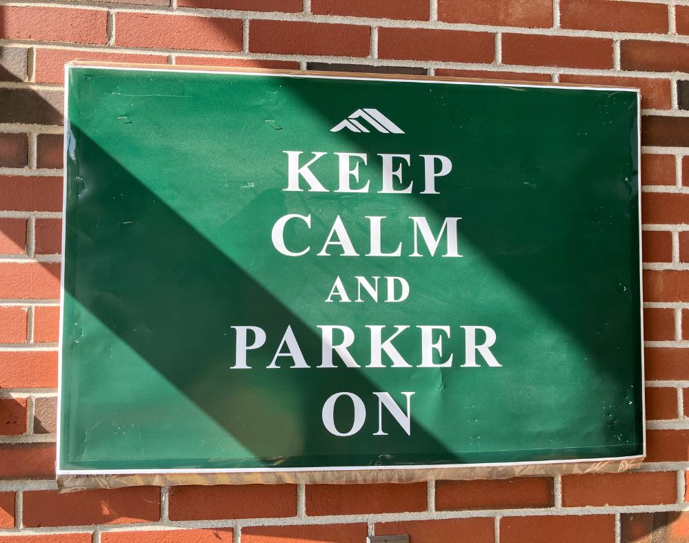 Competency-based innovative high school: Grren sign on red brick wall that reads, "Keep Calm and Parker On" in white, all caps letters.