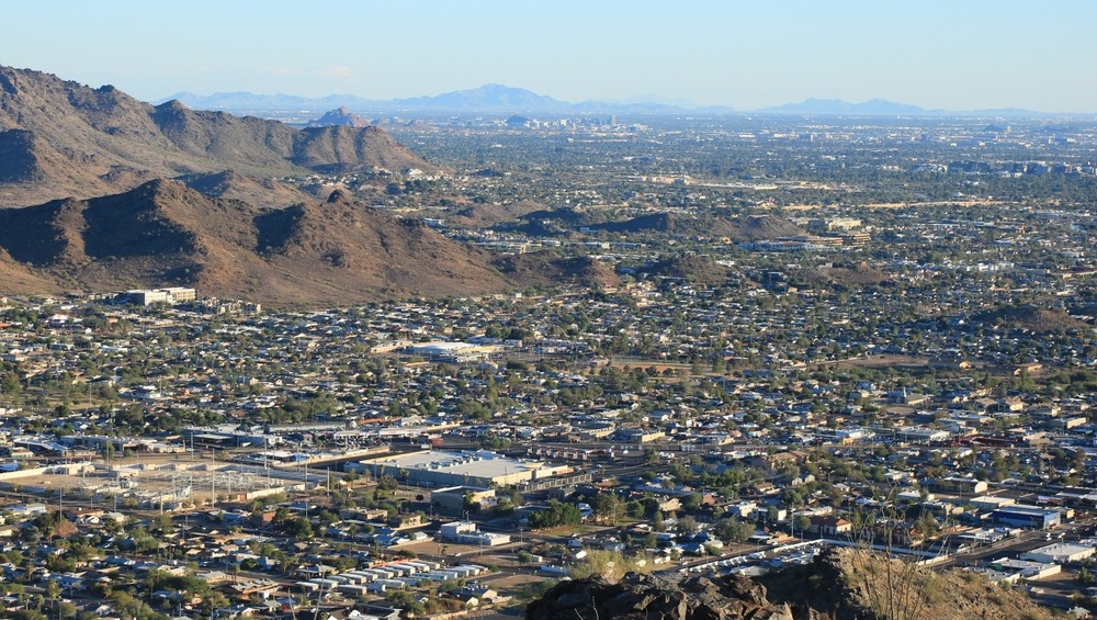 Long shot of Greater Phoenix Metro area surrounded by low, brown mountains as seen from the North looking South-East on late afternoon