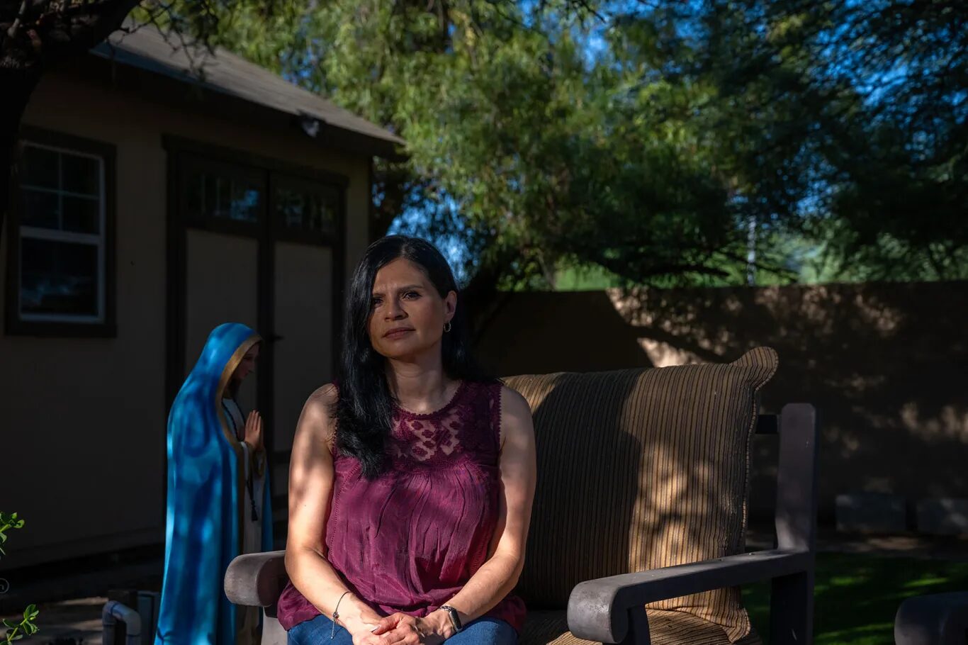 Latino voters gun reform Arizona: Woman with long dark hair sits in shade of tree in rose top with hands folded in lap