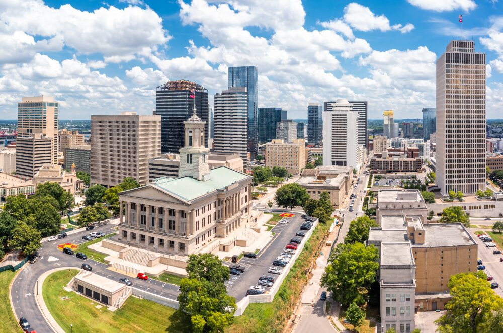 Free college tuition: Long view of traditional off-white multi-story building surrounded by a parking lot, other city buildings and skyscrapers.