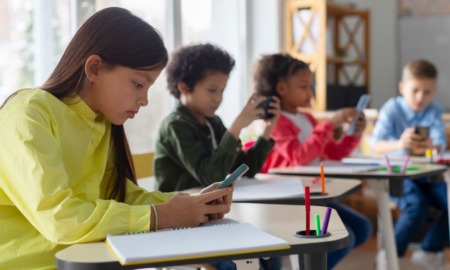 School cell phone bans hit most states: group of young students on their phones in classroom