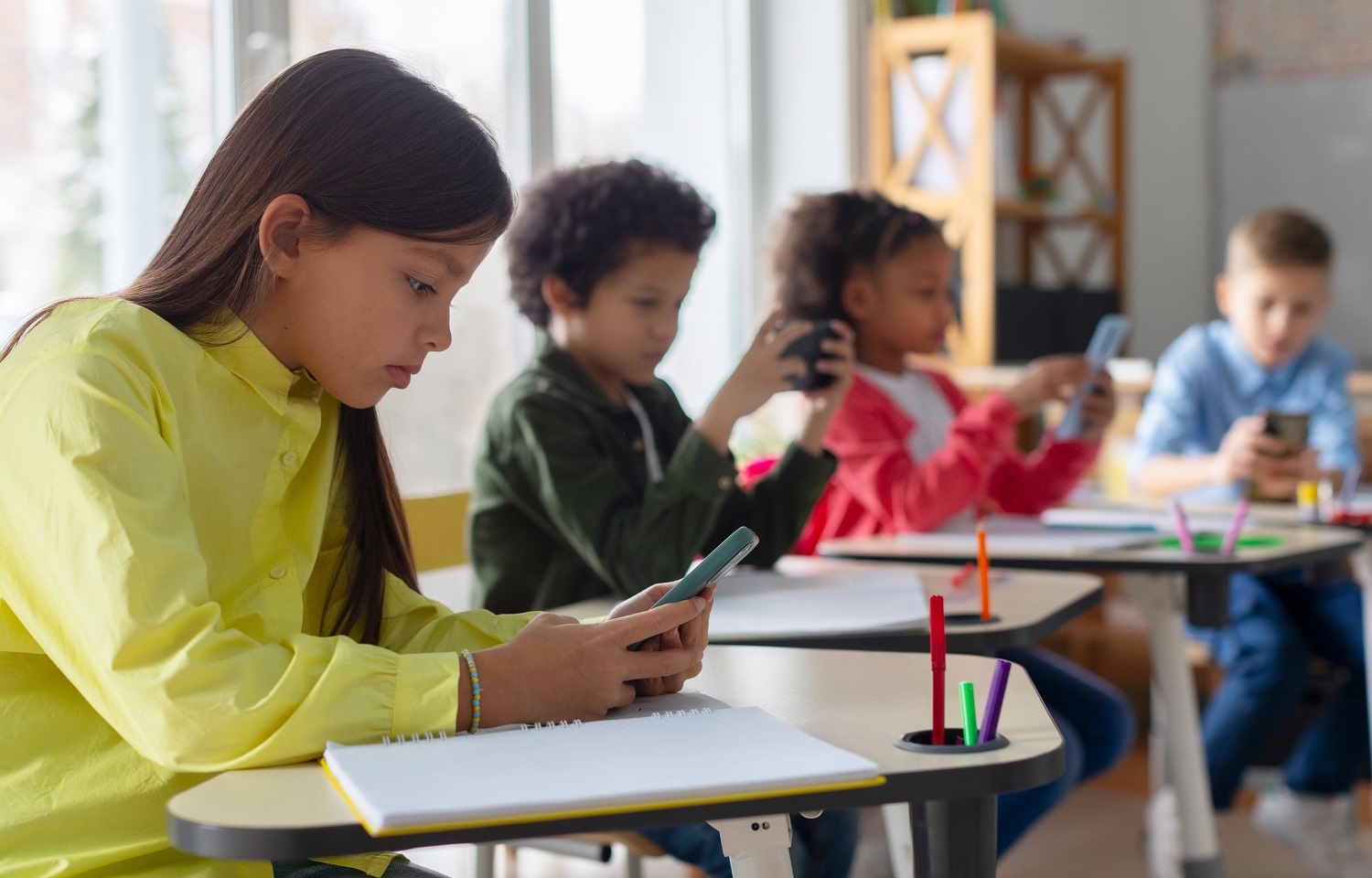 School cell phone bans hit most states: group of young students on their phones in classroom