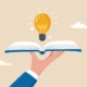 Opportunity makers education report: graphic of hand holding open book with lightbulb hovering above