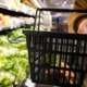 Did families miss out on federal funds to help feed their children last summer: hand holding an almost empty shopping basket with produce aisle in the background