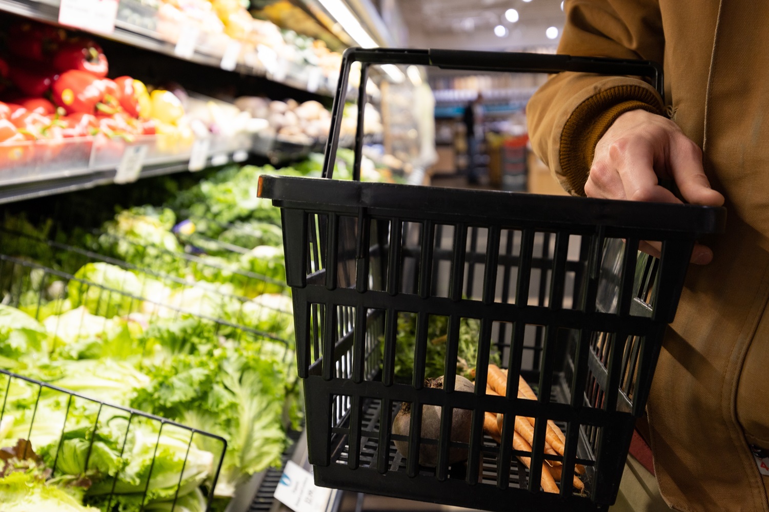 Did families miss out on federal funds to help feed their children last summer: hand holding an almost empty shopping basket with produce aisle in the background