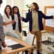 Mixed algebra class experiment: Group of young teens stand around display board watching male teacher in dark sport coat and tan pants explain an algebra formula on a white paper pad