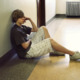 Kentucky foster kids in offices: Older teen boy sits on floor in office hallway