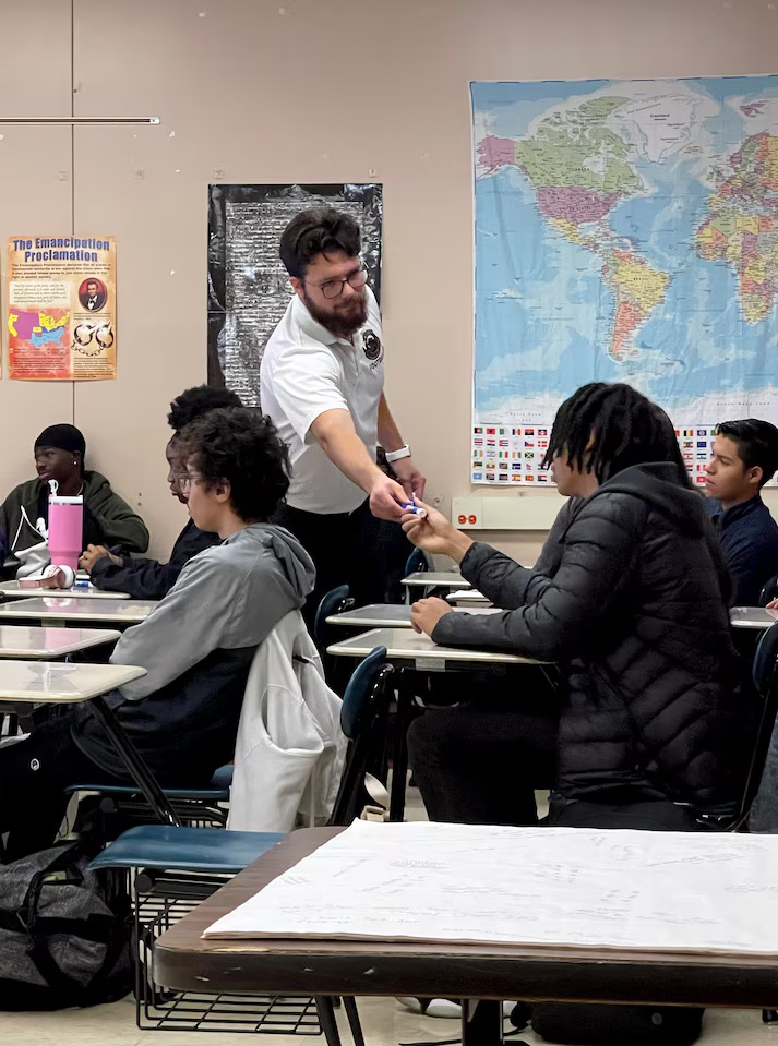 Teachers toss their lesson plans, give students the floor to grapple with Trump win: teacher handing marker to student in classroom