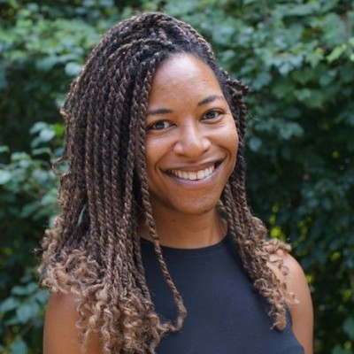 College listening cohort: Headshot Black woman with long light brown dreds in front of greenery