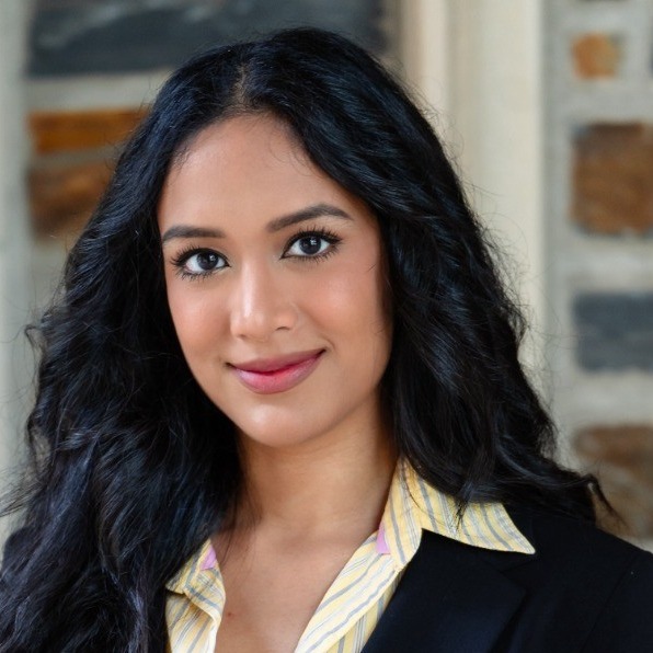 AI in College: Young woman with long, curly black hair in black suit jacket with white and yellow striped blouse